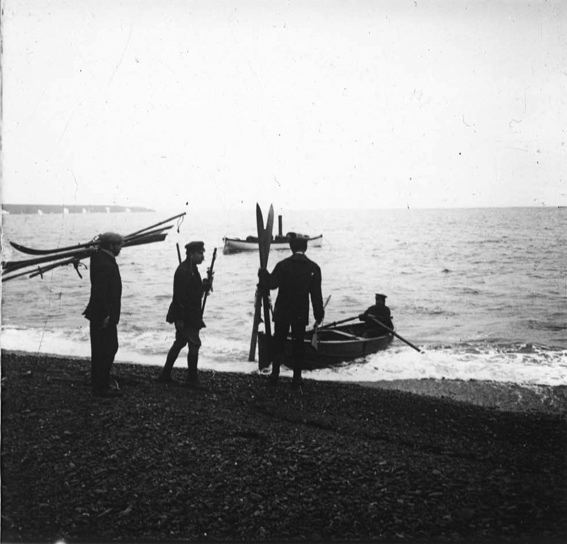 plaque de verre photographique ; Trois hommes qui embarquent ou débarquent de l’annexe