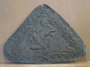Bas relief triangulaire ; Soldat assis avec enclume et marteau