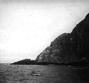 plaque de verre photographique ; Autre type de canot avec un homme à bord se dirigeant vers un promontoire rocheux
