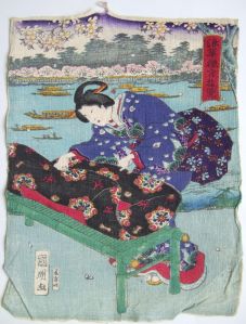 Femme pliant un drap noir sur un petit meuble vert. (titre factice)