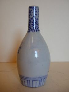 Petite bouteille à décor de fleurs bleu sur fond blanc. (titre factice)