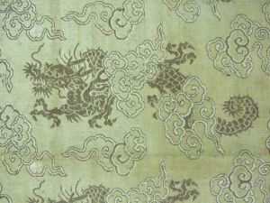 Tissu brodé de motifs repétés de dragons et nuages sur fond doré, doublure beige avec motifs dans la trame. (titre factice)