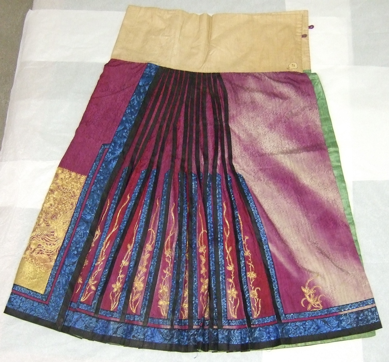 Jupe chinoise destinée à accompagner une robe. Violette, plis bleus et violets, motifs au fil d'or. Doublure verte. (titre factice)