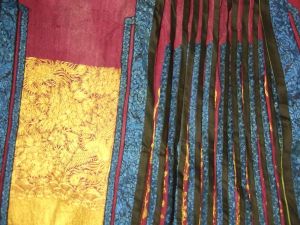 Jupe chinoise destinée à accompagner une robe. Violette, plis bleus et violets, motifs au fil d'or. Doublure verte. (titre factice)