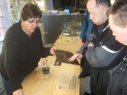Prise lors d'une visite adaptée au musée du verre et du cristal de Meisenthal, la photographie figure la guide en train de faire toucher un support à deux visiteurs handicapés.